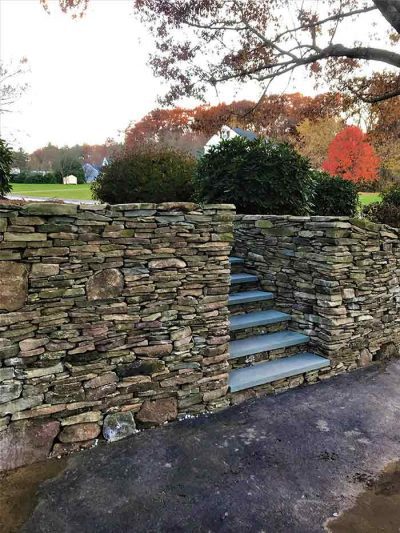 Veneer stone wall and steps with bluestone treads in front yard.