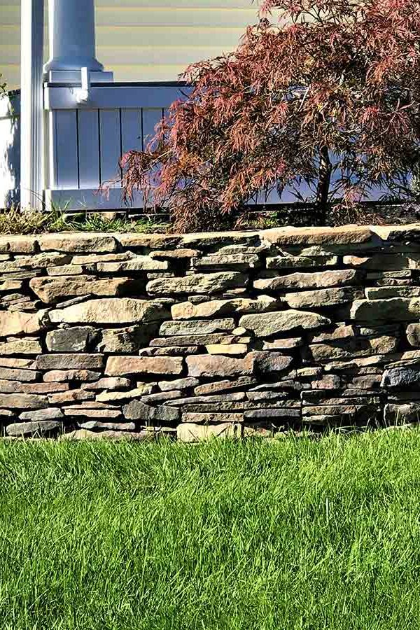front yard natural fieldstone retaining wall with planting beds