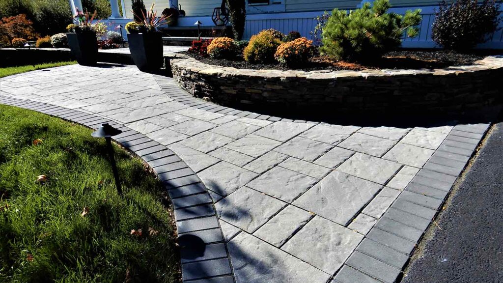 front home paver walkway entrance and fieldstone retaining wall around garden bed
