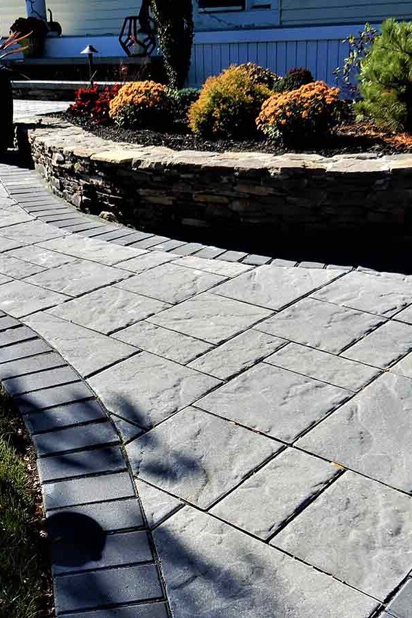 front home paver walkway entrance and fieldstone retaining wall around garden bed