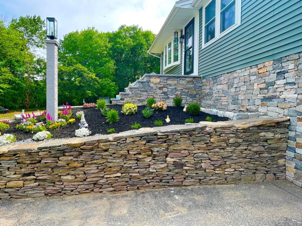 veneer home foundation with retaining wall and granite lamp post