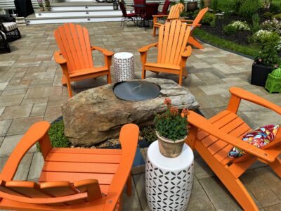 natural stone gas fire pit on paver patio with chairs