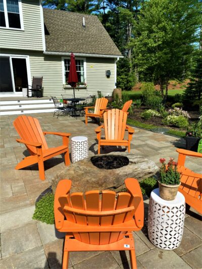 back yard paver patio landscape with stone fire pit and Adirondack chairs