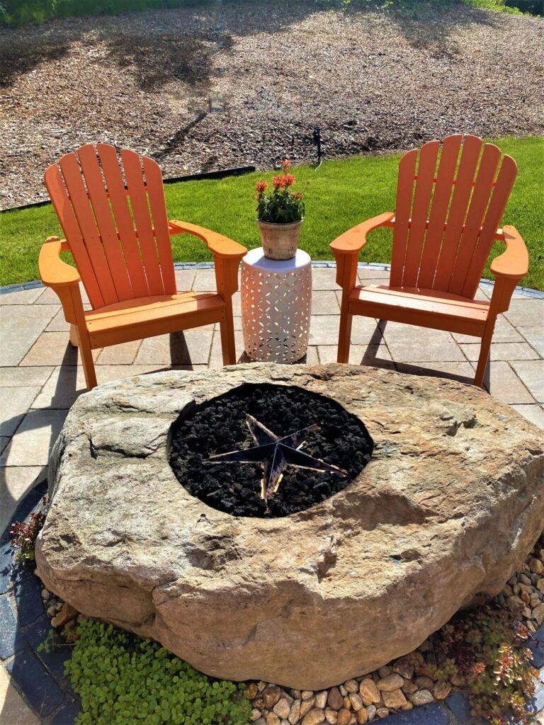 natural stone fire pit sitting area in back yard with chairs