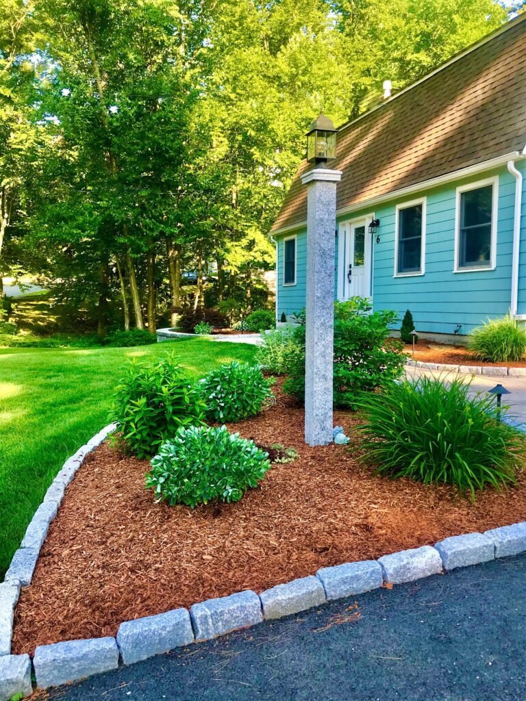 front granite lamp post with cobblestone bordered planting bed