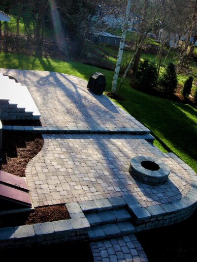 tiered backyard paver patio with fire pit and steps